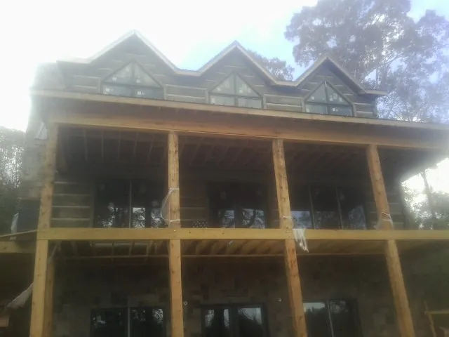 Dormers and porch framing on a large log home under construction — Roof Coating work by our crew in East Freetown