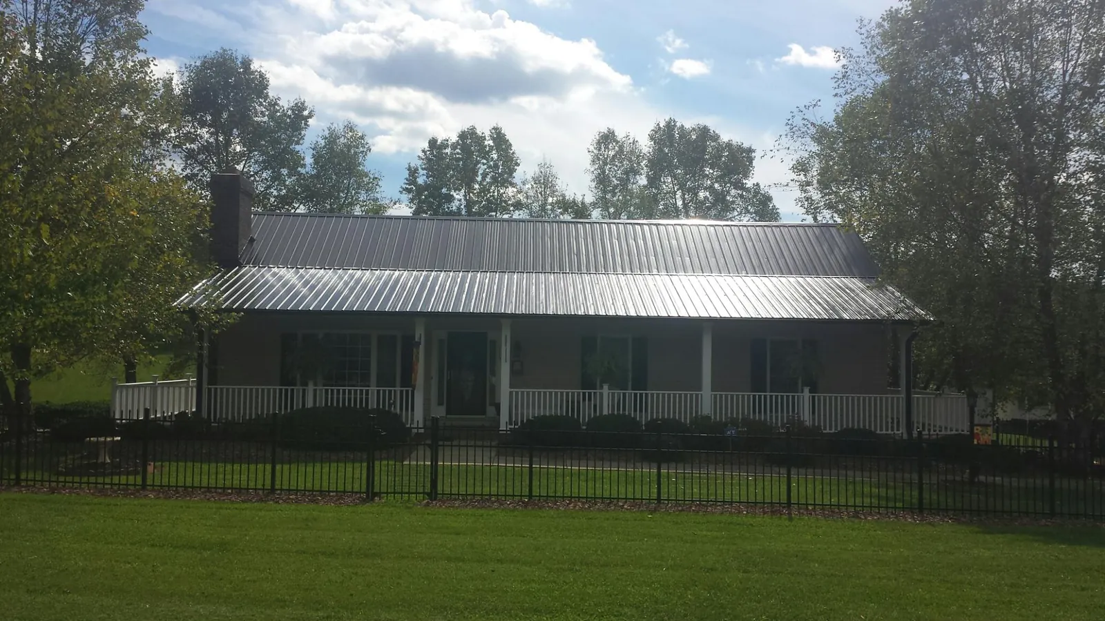 Gray metal roof on a brick ranch with a full width front porch — Gutter Guard Installation work by our crew in East Freetown