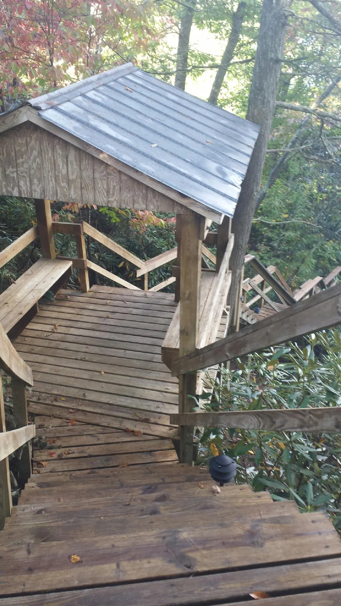 Metal roofed shelter over wooden steps on a wooded walkway — Skylight Repair & Installation work by our crew in East Freetown
