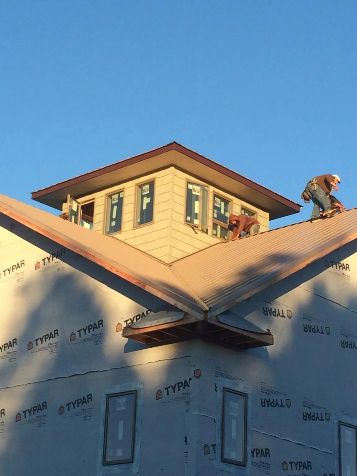 Roofers working around a rooftop cupola on a new metal roof at sunset — Roof Waterproofing in East Freetown by Roofing Brothers